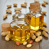 Two glass bottles of oil surrounded by peanuts and peanut shells
